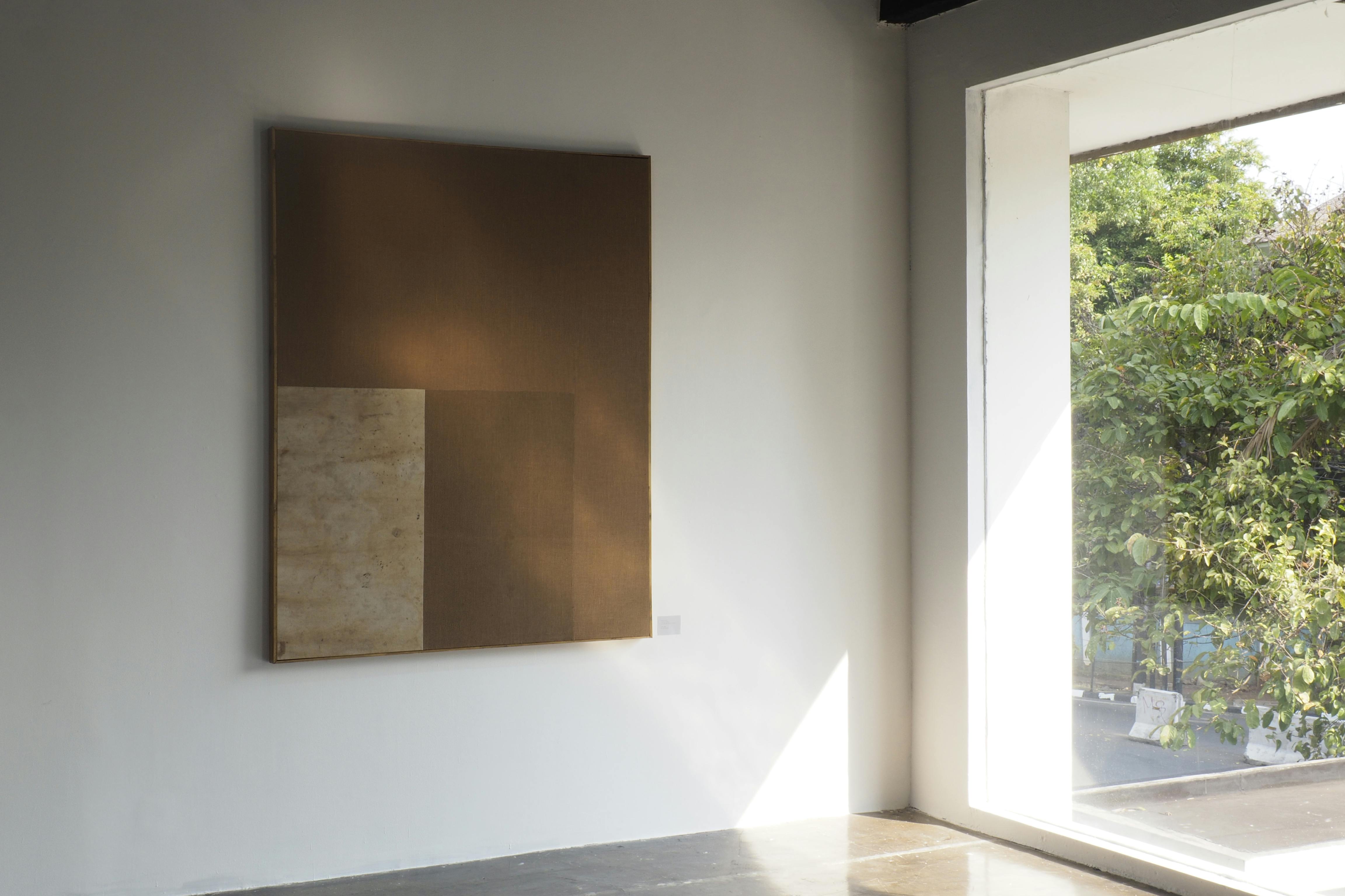abstract earthtone woven artwork on display on a wall beside a window