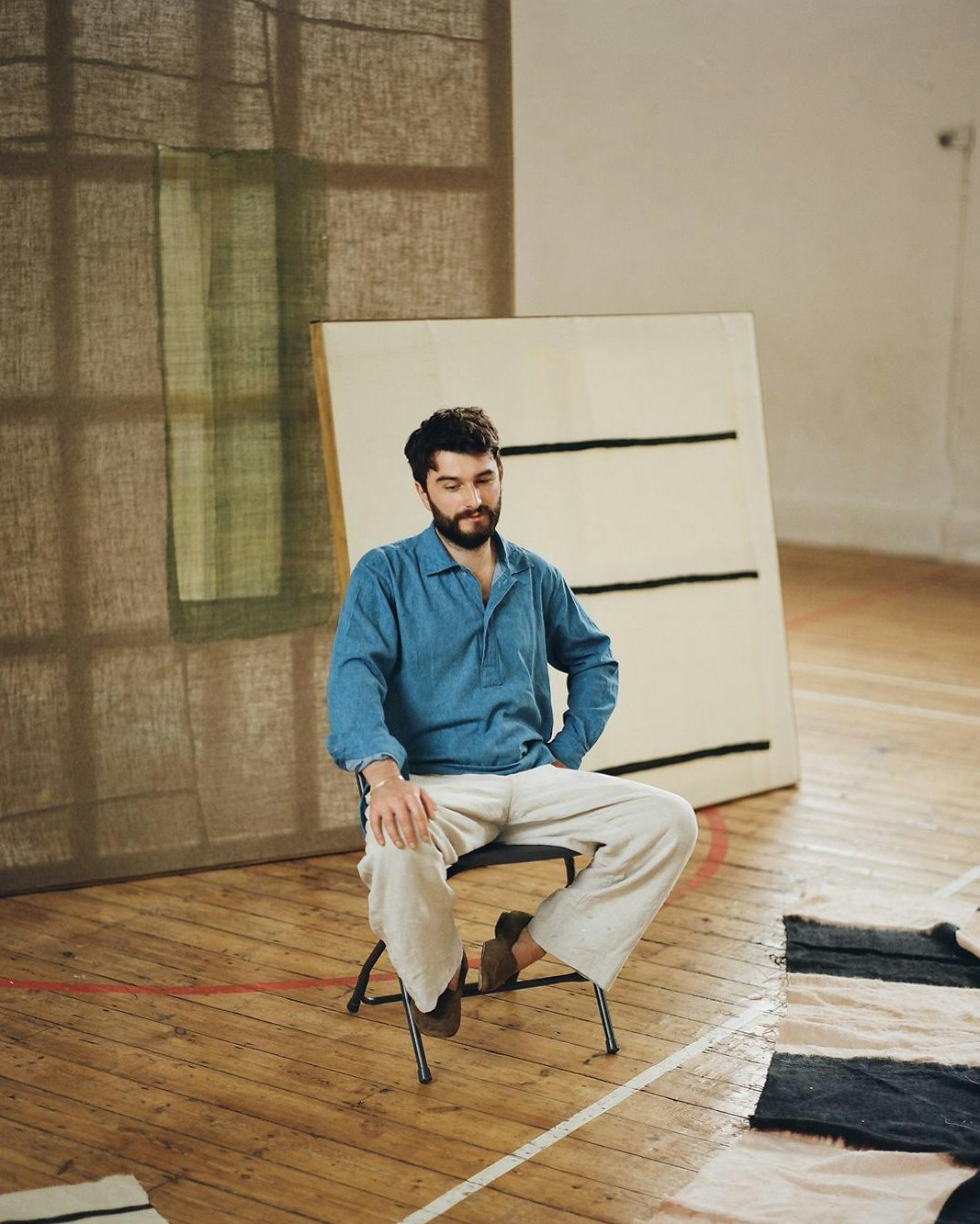 textile artist seated on studio surrounded by handwoven works
