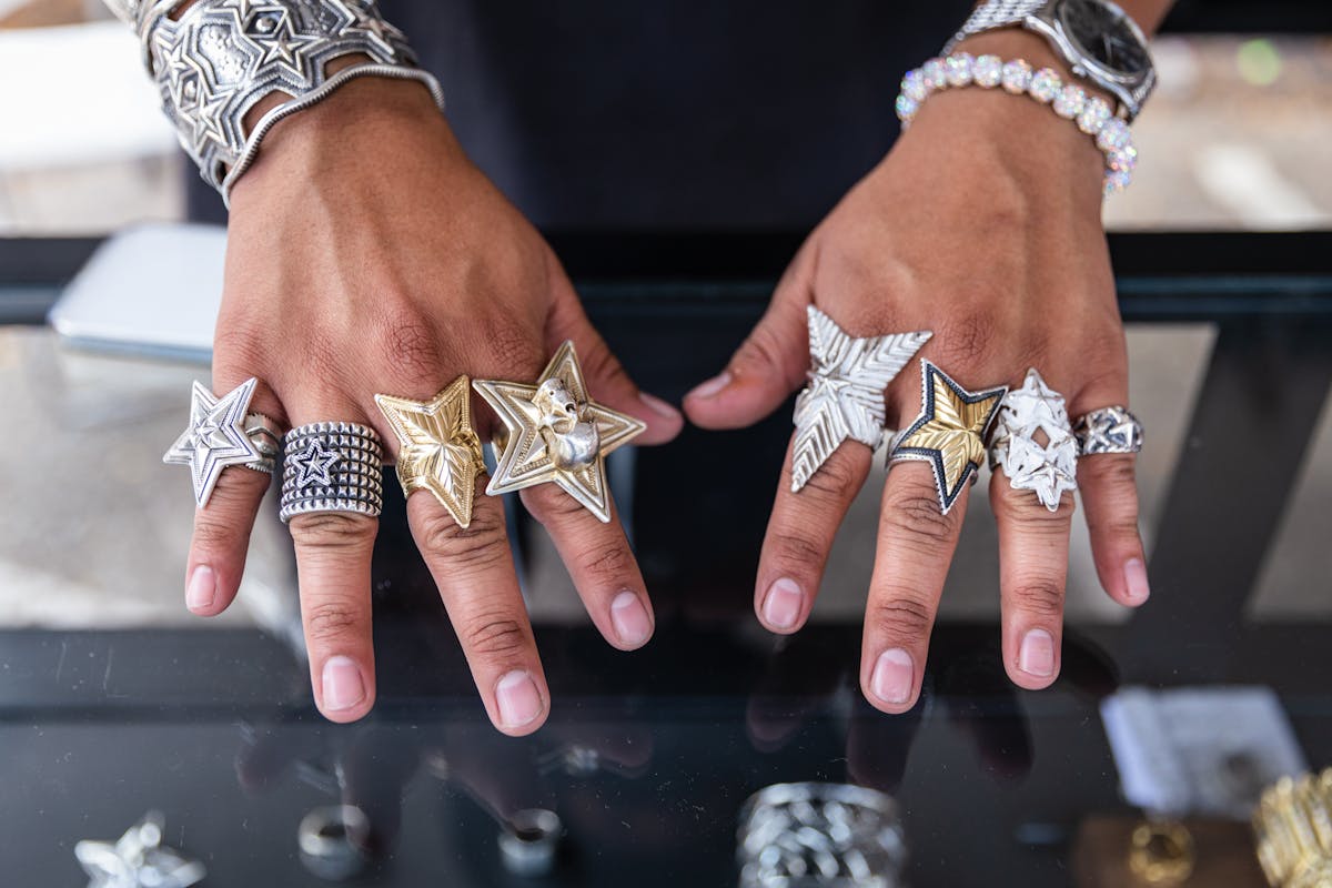 two hands with fingers adorning with handmade metal star rings