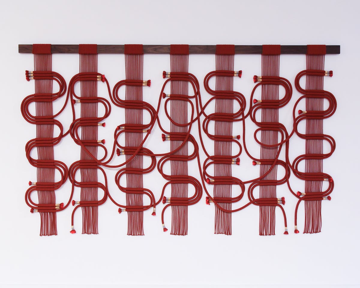 conceptual weaving made from columns of red string beset with interlocking loops of red rope