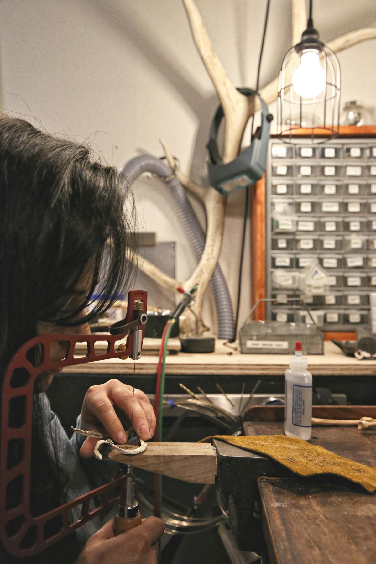 jeweler working at bench with saw in studio