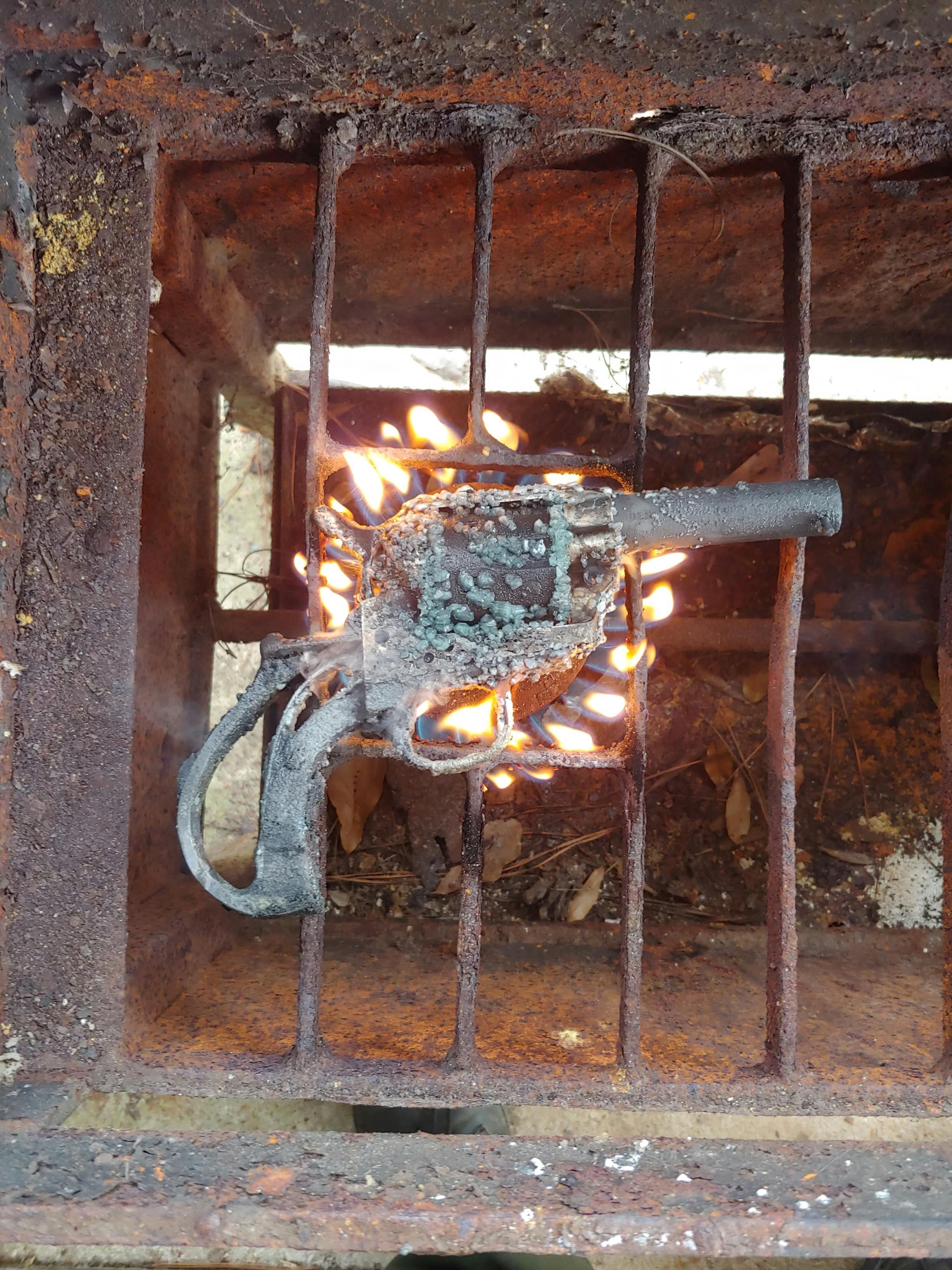 revolver handgun with crystals forming on it while roasting over a burner on a grill