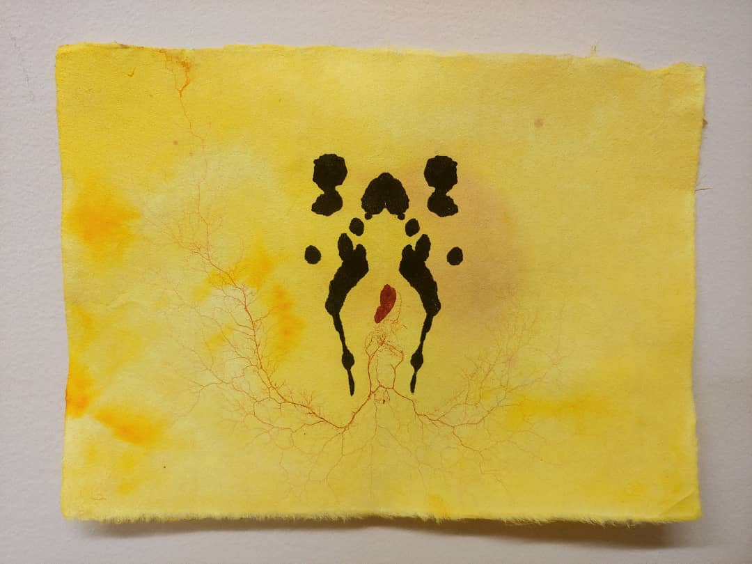 inkblot drawing on yellow paper with rust-colored pattern left by slime mold