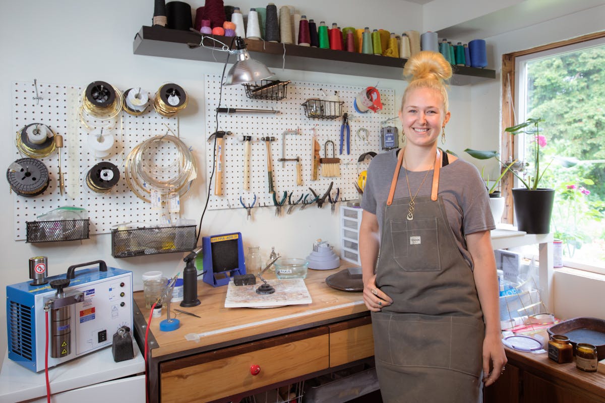 Seattle-based jewelry maker Twyla Dill in her studio with metal tools and spools of thread