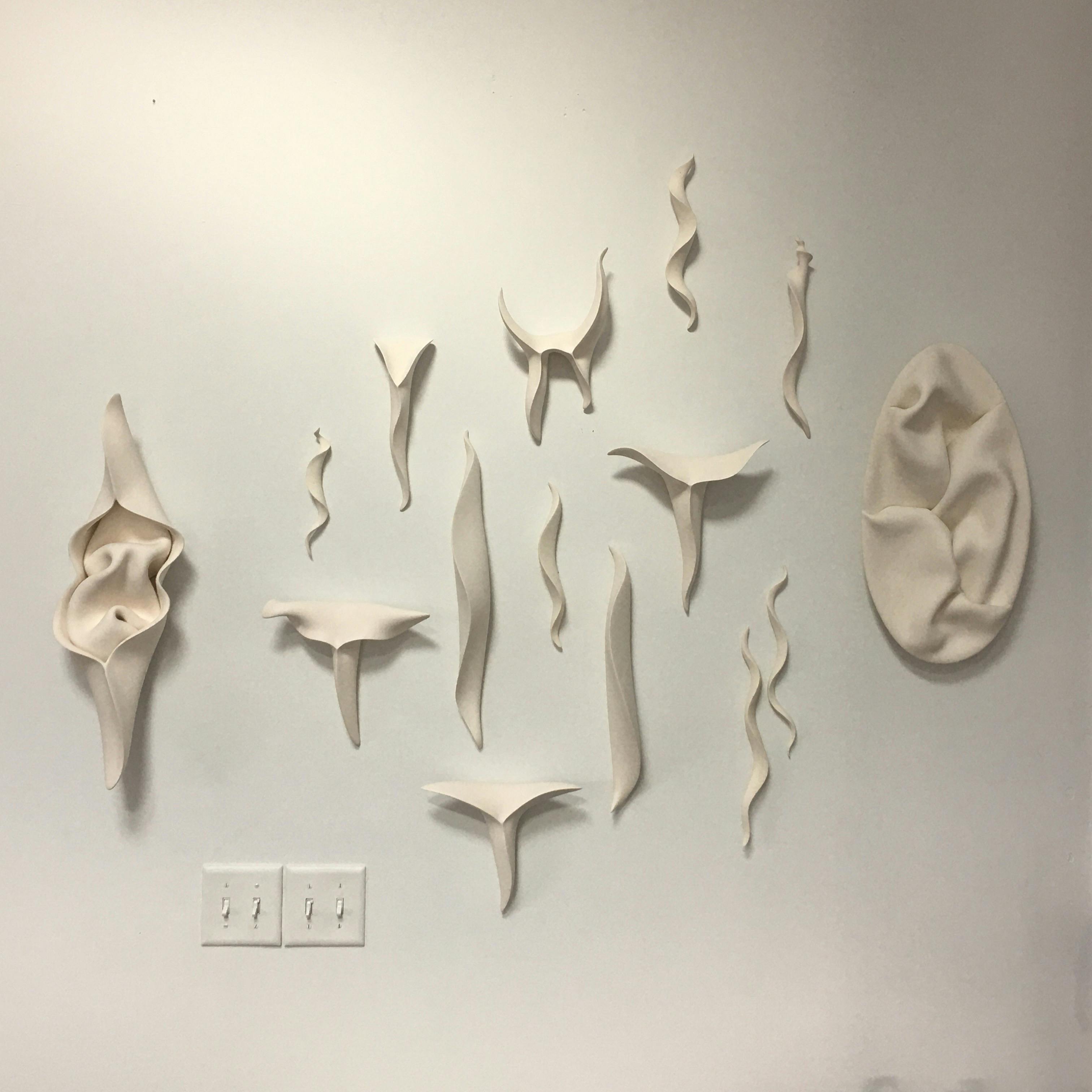wall with various ceramic sculptures by jeannine marchand