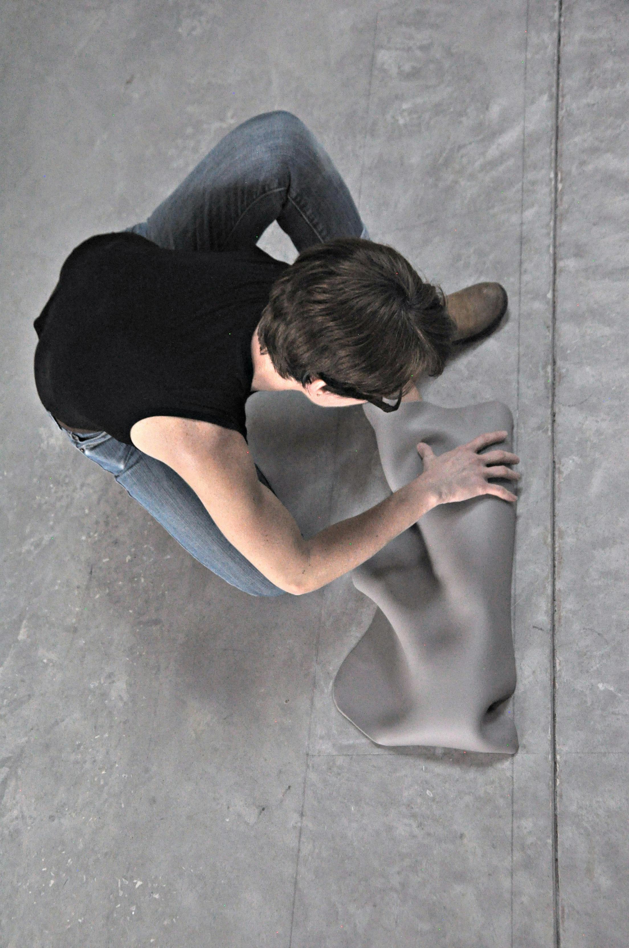 overhead view of jeannine marchand seated on floor working on clay ceramic sculpture