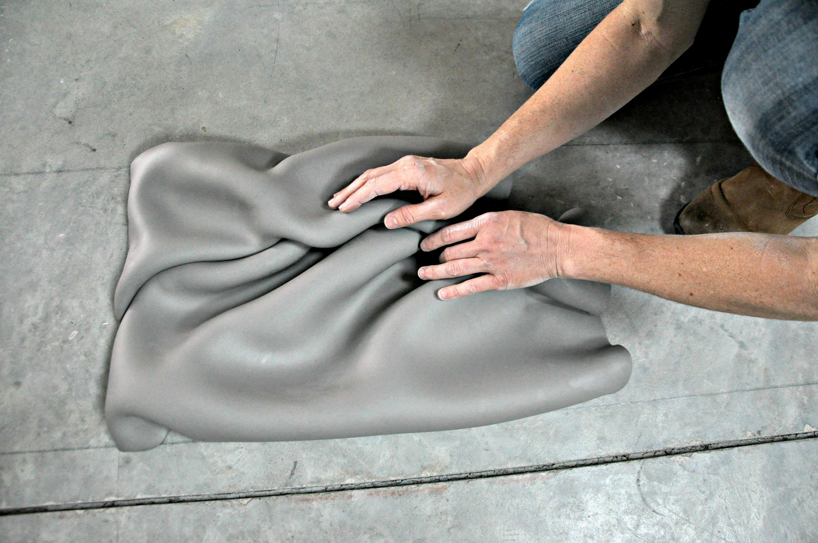 jeannine marchands hands working on clay sculpture with folds