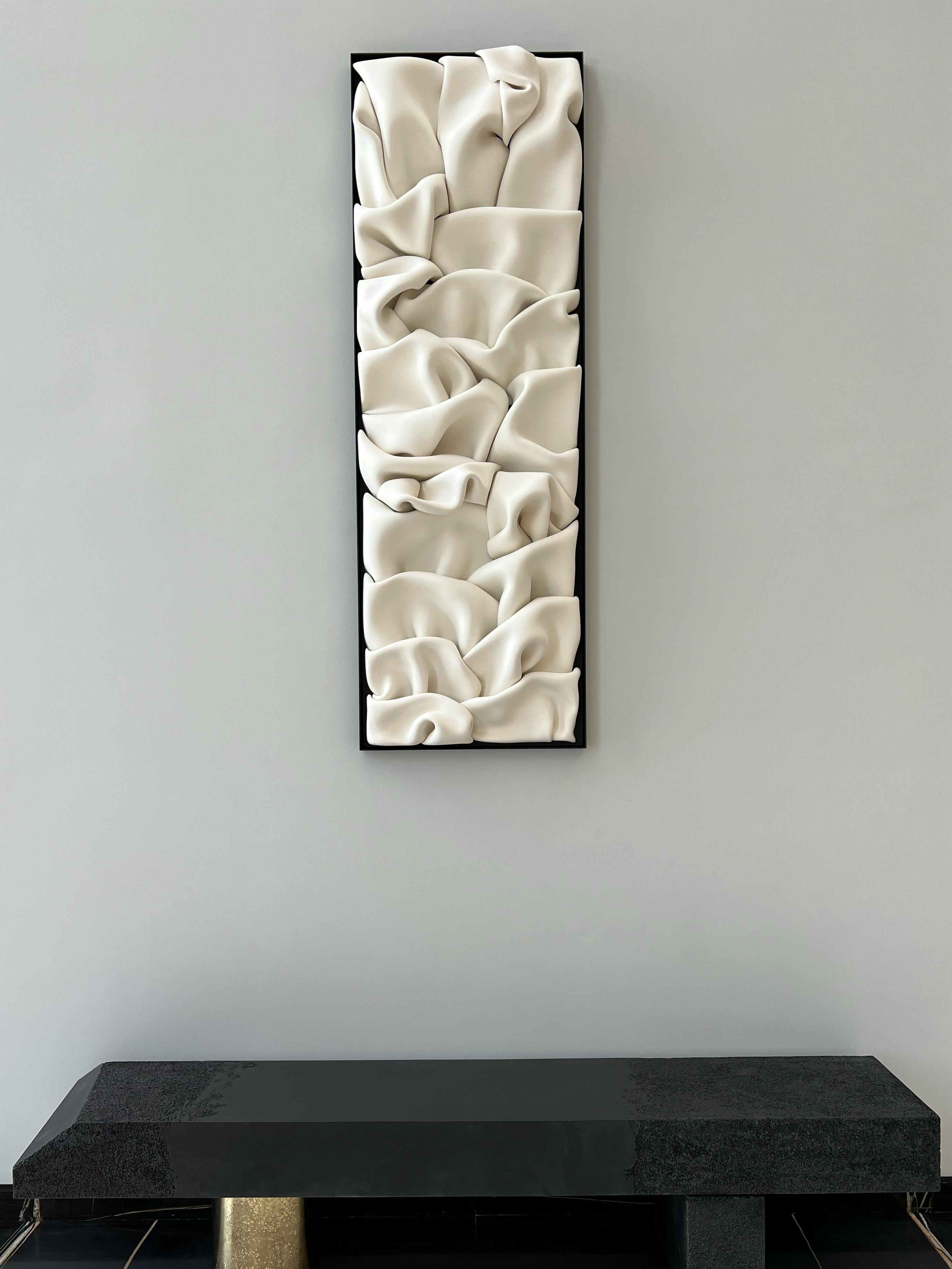 ceramic sculpture by jeannine marchand mounted on wall above bench