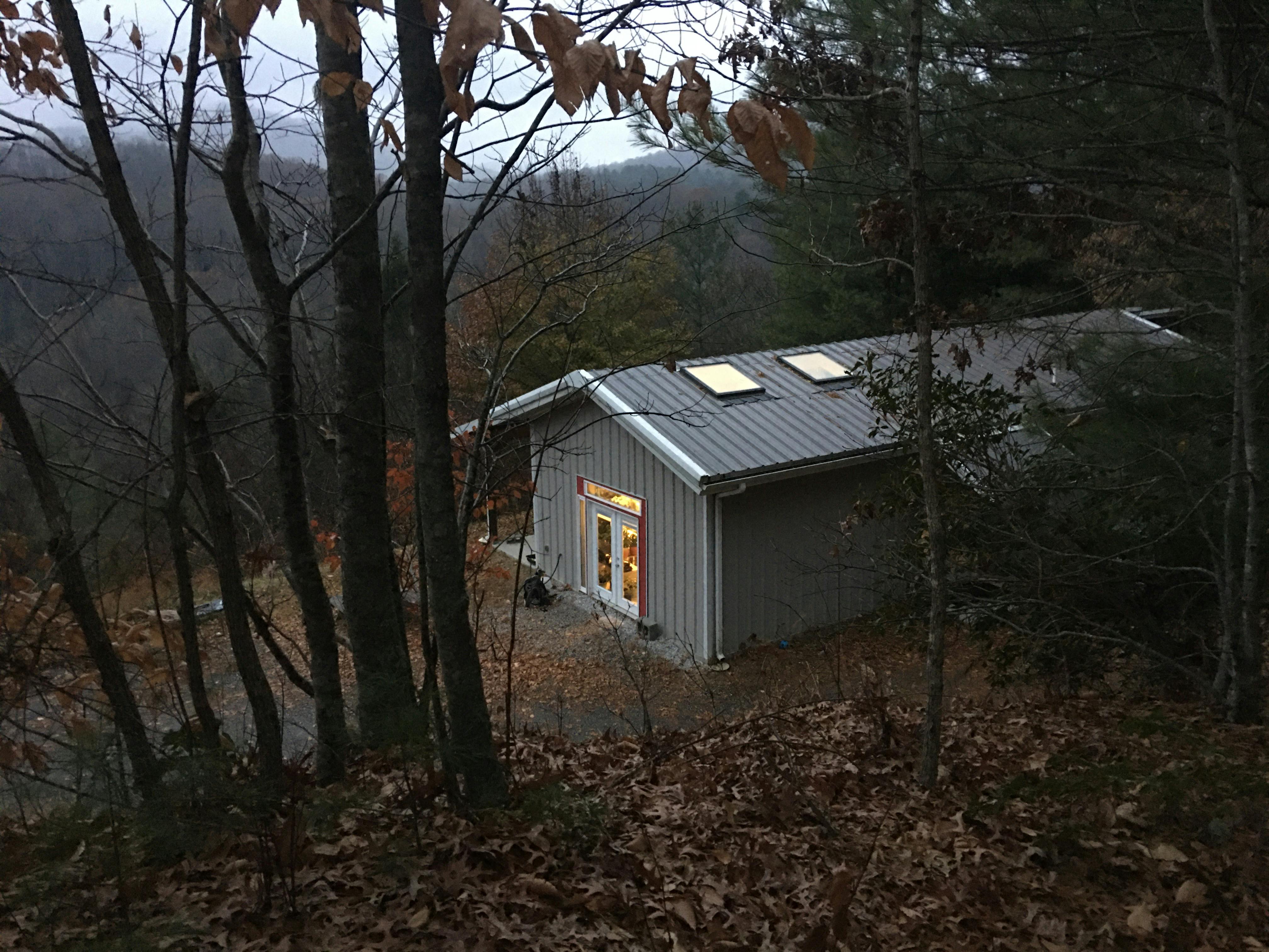 studio nestled in misty woods on hillside at dusk