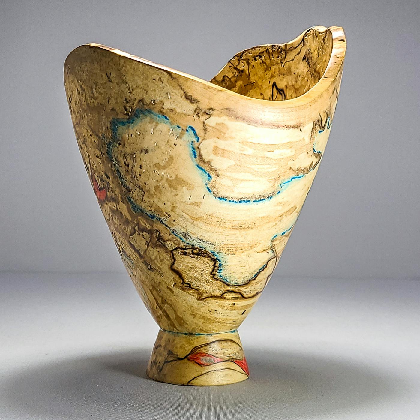 wooden vessel with subtle red and teal coloration in grain