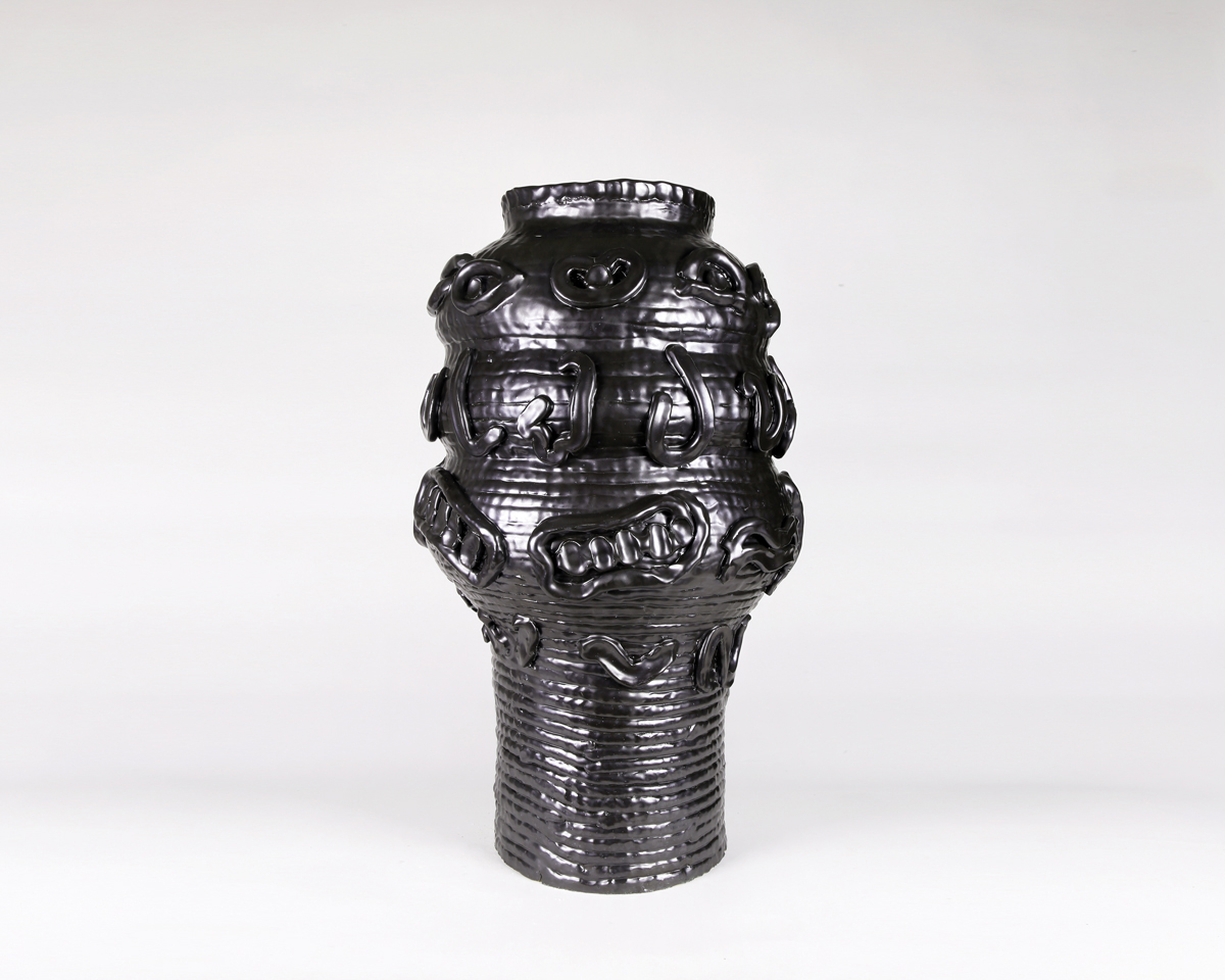 shiny black ceramic vessel with coiled texture and various shapes on the surface