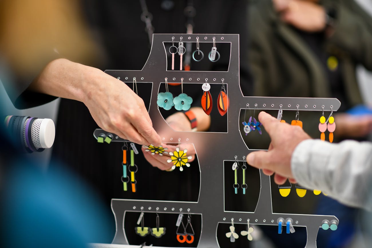 hands pointing at a display of handmade jewelry